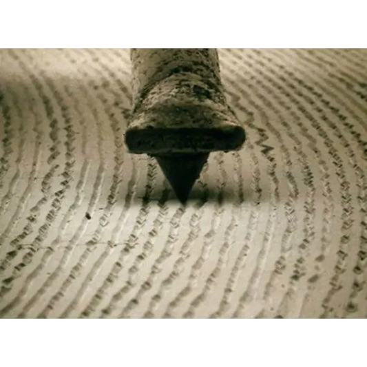 Close-up of a stylus tip and cantilever tracking a vinyl record groove
