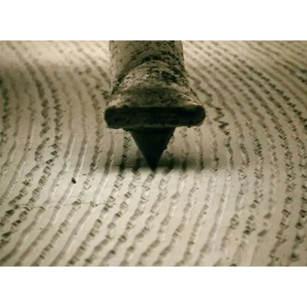 Close-up of a stylus tip and cantilever tracking a vinyl record groove